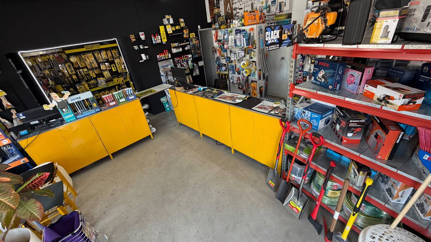 Interior de Ferretería Adamoli: mostrador amarillo, estanterías con herramientas eléctricas, palas, mangueras y exhibidor Ingco