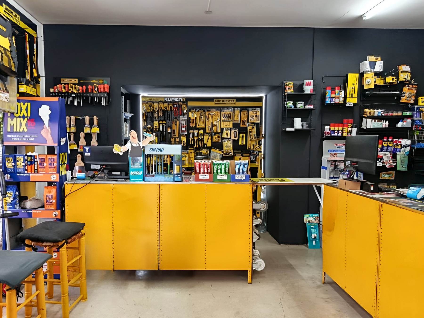 Mostrador amarillo de Ferretería Adamoli con el exhibidor de herramientas al fondo